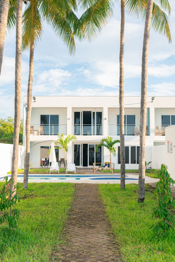 Bright modern villa surrounded by tropical palm trees and a pool, ideal for summer getaways.