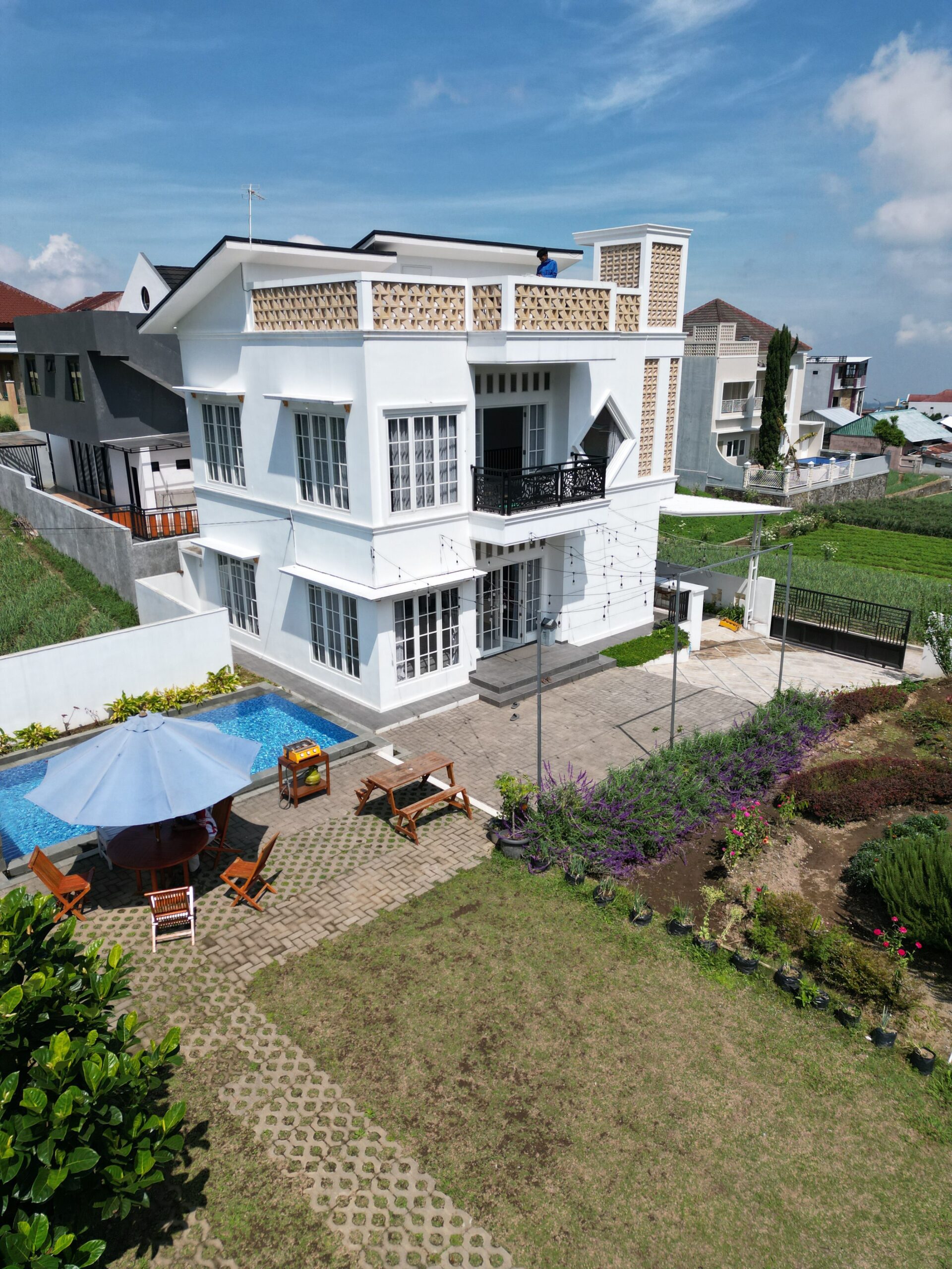 Aerial view of a modern suburban house with a private pool and lush garden.