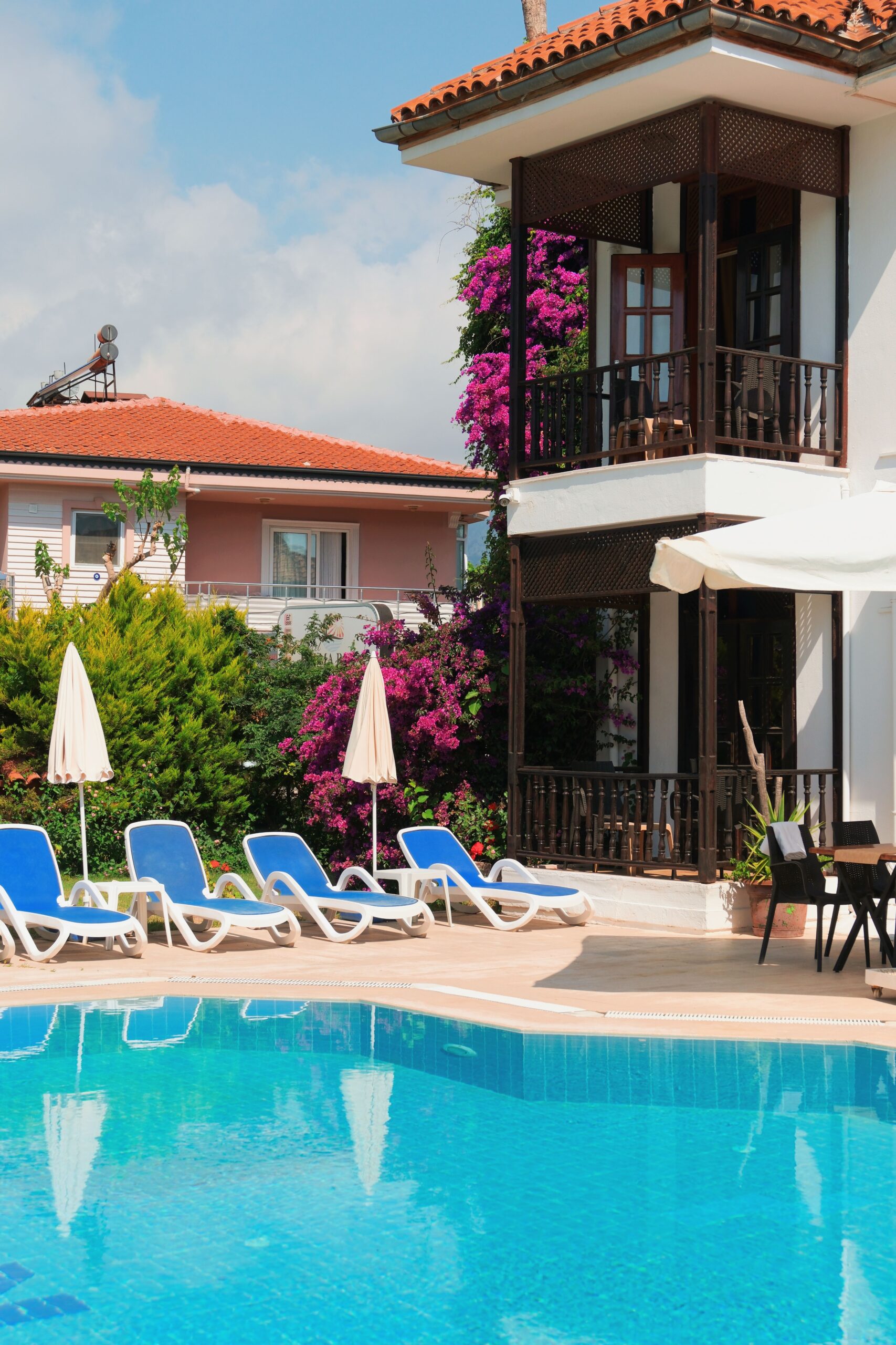 Charming villa with a pool surrounded by vibrant flowers and elegant architecture, ideal for a summer retreat.